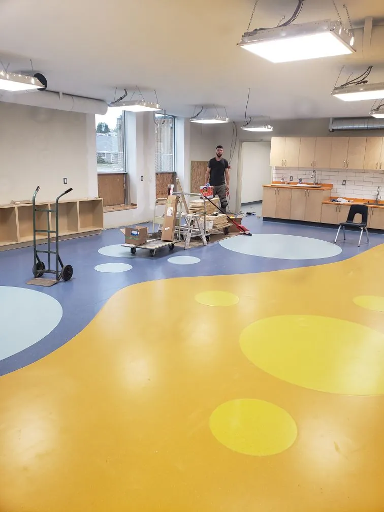 Custom heat-welded sheet vinyl floor with yellow and blue color blocks and inlaid circles installed by Geometrix Flooring & Design