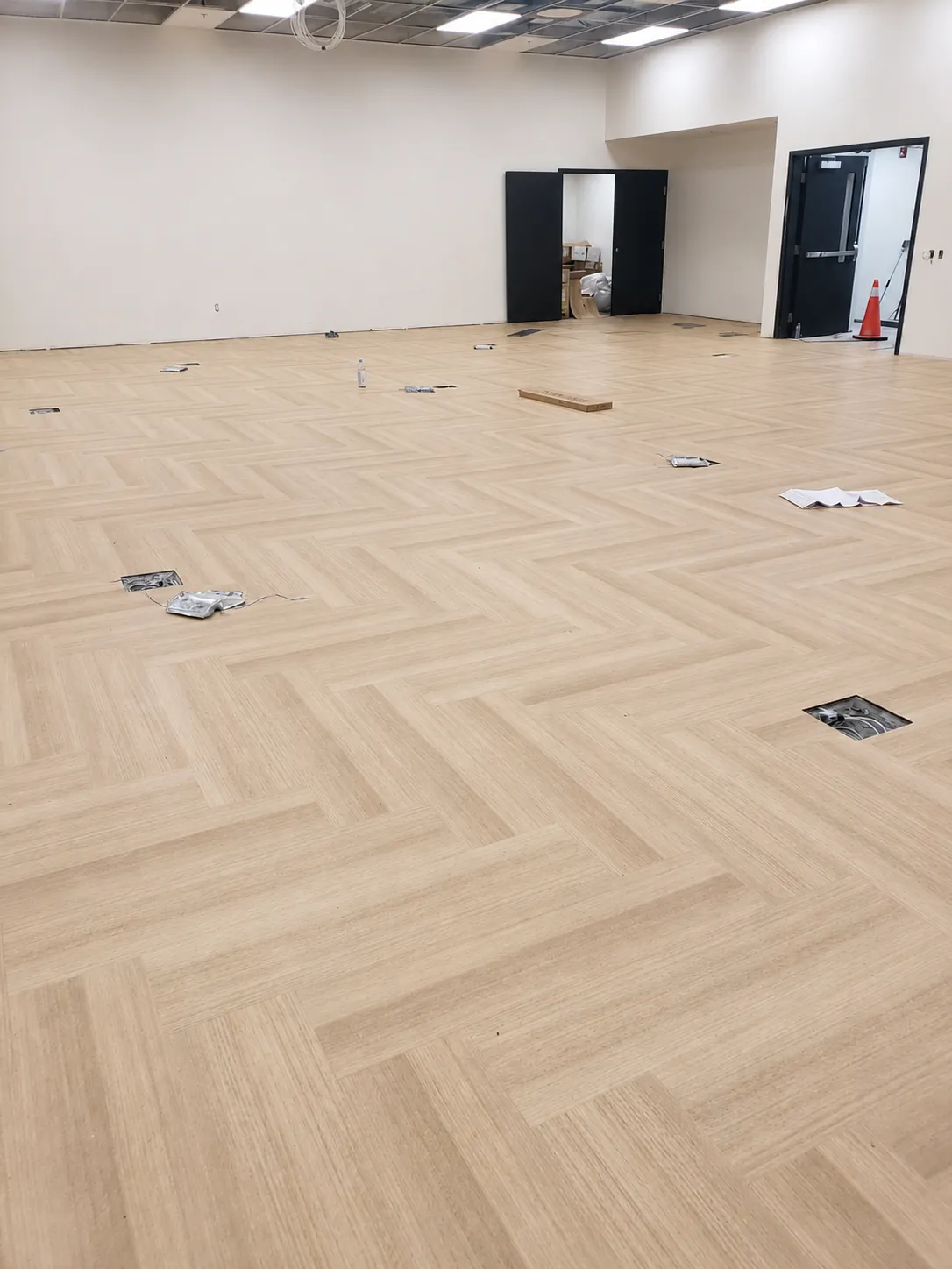 Close-up of wood-look herringbone luxury vinyl tile installed across a large open commercial space by Geometrix Flooring & Design
